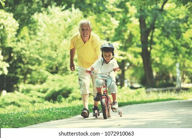 Happy Grandfather And Child Have Fun And Play In Park