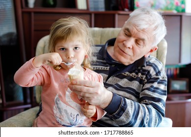 Happy Grandfather And Cute Little Toddler Granddaughter, Adorable Child Eating Together Ice Cream. Family Tasting Sweet Icecream, Baby Girl Feeding Senior Man.