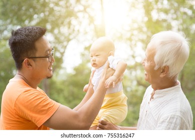 Happy Grandfather, Father And Baby Grandchild At Outdoors Park. Asian Multi Generations Family.