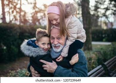 Happy grandfather having fun with his grandchildren in city park.
