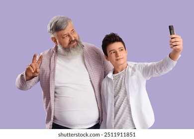 Happy grandfather with his cute grandson taking selfie on purple background - Powered by Shutterstock