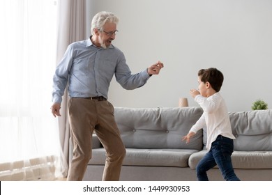 Happy Grandfather And Little Grandchild Dancing To Music Together, Excited Granddad And Cute Preschool Grandchild Having Fun At Home, Playing, Playing In Living Room, Family Funny Activity