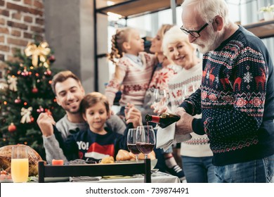 happy grandfather pouring wine into glasses for his family on christmas - Powered by Shutterstock