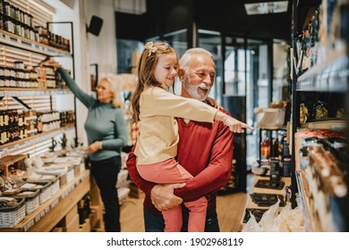Happy grandfather shopping together with his granddaughter in grocery store or supermarket.