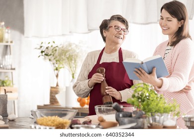 Happy Grandma Cooking With Her Granddaughter In Modern Kitchen