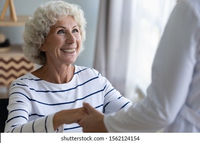 Happy Grandma Holding Hand Of Nurse Caregiver Helping Senior Patient Getting Up Taking Care Of Disabled Handicapped Injured Old Adult Elder Woman Having Disability Health Problem, Eldercare Concept