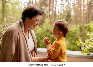 Happy grandmother and grandson enjoy time together. Positive middle age woman playing with little, cute grandchild, laughing, having fun. 50-year-old grandma with grandkid. Multi-generational family.
