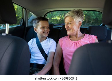 Happy grandmother and grandson sitting in the back seat of car - Powered by Shutterstock