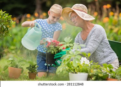 Happy grandmother with her granddaughter gardening on a sunny day - Powered by Shutterstock