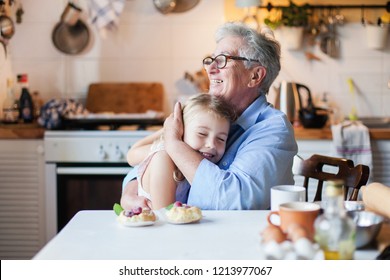 Happy grandmother is hugging granddaughter in cozy home kitchen. Family is cooking together. Senior woman and cute little child girl are smiling. Kid is enjoying kindness, warm hands, care, support. - Shutterstock ID 1213977067