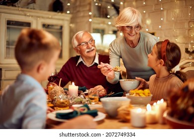 Happy grandmother serving food while having Thanksgiving dinner with her family at home. - Powered by Shutterstock