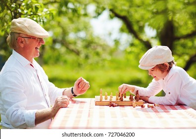 happy grandpa and grandson playing chess in spring garden
