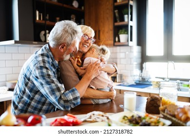 Happy Grandparents With Grandchildren Making Breakfast In Kitchen