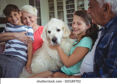 Happy grandparents and grandchildren sitting with pet dog at home