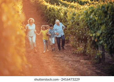 Happy grandparents and grandchildren walking through a vineyard - Powered by Shutterstock