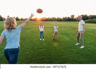 happy grandparents playing american football with grandchildren in park - Powered by Shutterstock