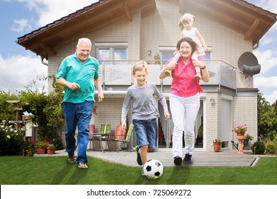 Happy Grandparents Playing Soccer With Their Grandchildren Outside Their House