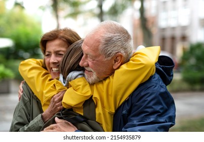 Happy grandparents with preteen grandddaughter hugging together ourtdoors in town street - Powered by Shutterstock