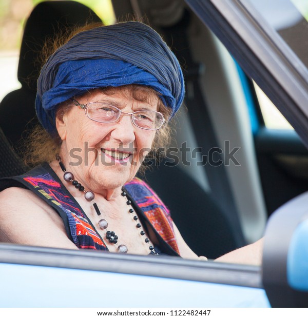 Happy granny\
at car. Old woman driving. Seniors\

