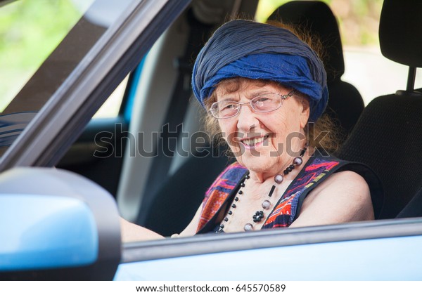 Happy granny\
at car. Old woman driving. Seniors\
