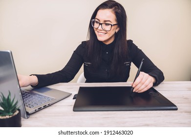 Happy graphic designer woman looking at the laptop screen and using digital graphic tablet while working at home office. Female retoucher working on digital graphic  tablet. - Powered by Shutterstock