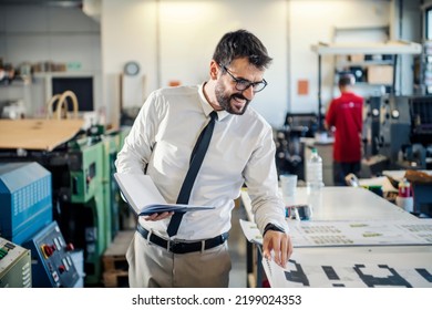 A Happy Graphic Engineer Looking At Printing Proof At Printing Shop.