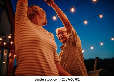 Happy Gray Haired Senior Retired Couple, Dancing Outdoors. Smiling Elder Man And Woman Enjoying Evening In The Backyard