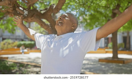 Happy grey-haired hispanic man enjoying the outdoors with arms outstretched in a sunny city park. - Powered by Shutterstock