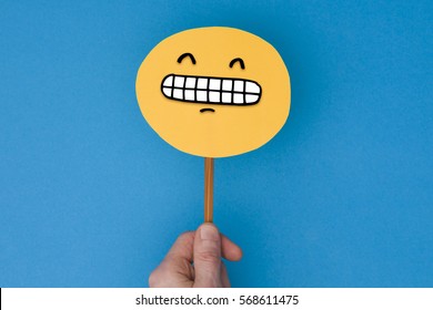 Happy Grinning Emoji. Male Hand Holding A Yellow Emotion Face With A Hand Drawn Expression