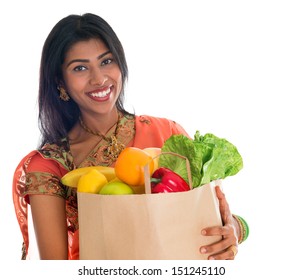 Happy Grocery Shopper. Portrait Of Beautiful Traditional Indian Woman In Sari Dress Holding Paper Shopping Bag Full Of Groceries Isolated On White.