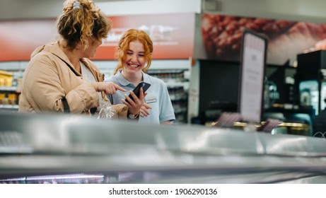 Happy Grocery Store Employee Helping Female Customer. Young Employee Helping Female Customer At The Supermarket.