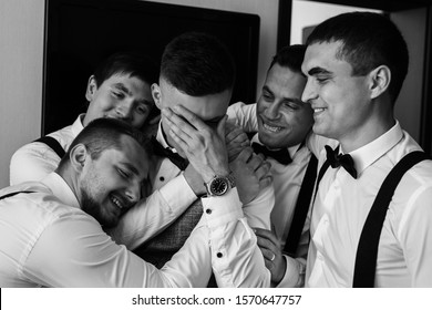 Happy Groom And Joyful Groomsmen Embracing After Wedding Ceremony. Black And White Wedding Photography