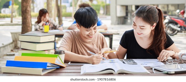 A happy group of attractive young people is tutoring exams with study books, sitting on the study table. Student group and tutoring education concept. banner size