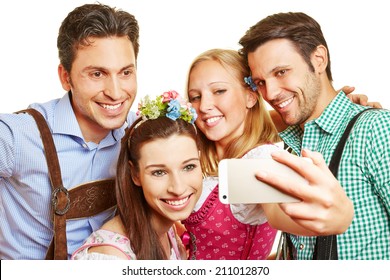 Happy group in bavaria at Oktoberfest taking a selfie with smartphone