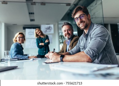 Happy group businesspeople during presentation  Colleagues looking at camera   smiling 