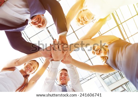 Happy group of businesspeople stacking their hands in cooperation