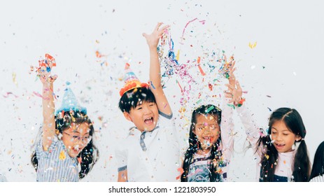 Happy Group Of Children Having Fun At Party.birthday Party And Christmas Dinner.Happy Kids Throwing Colorful Confetti In A Room.