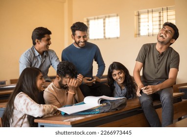 Happy group of college friends making fun of each other. Distracted from studying diverse guys and girls laughing, having fun together at classroom while preparing for exams.Education concept  - Powered by Shutterstock