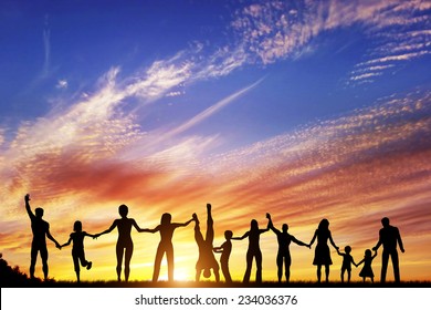 Happy Group Of Diverse People, Friends, Family, Team Standing Together Holding Hands And Celebrating Success. Sunset Sky