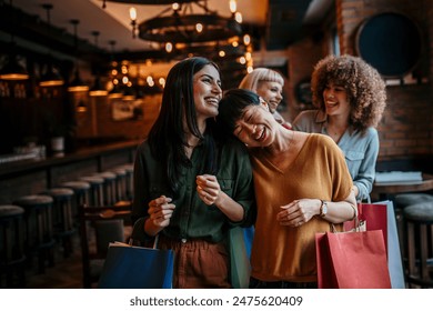 Happy group of diverse women entering a chic restaurant, their arms full of shopping bags - Powered by Shutterstock