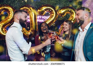 Happy group of friends celebrate New Year's Eve while drinking champagne on a party in a club - Powered by Shutterstock