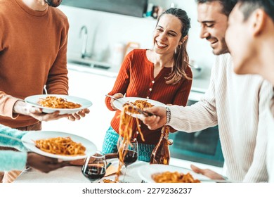 Happy group of friends eating pasta at home dinner party - Cheerful young people having lunch break together - Life style concept with guys and girls celebrating thanksgiving - Bright filter