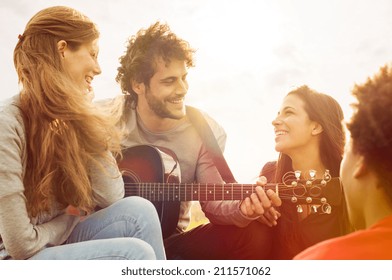 Happy group of friends enjoying the summer outdoor playing guitar and singing together - Powered by Shutterstock