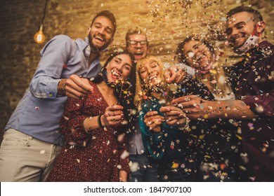 Happy Group Of Friends With Face Mask Celebrating New 2021 Year - Confetti Falling In The Air - Young People With Sparklers Making New Year Party At Home - Focus On Sparklers.