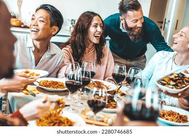 Happy group of friends having dinner party at home - Cheerful young people having lunch break together - Life style concept with guys and girls celebrating thanksgiving - Food and beverage lifestyle - Powered by Shutterstock