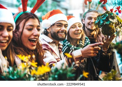 Happy group of friends having fun at Christmas Market souvenir shop - Cheerful young tourists enjoying winter holidays outside - Traditional culture and holidays concept - Shutterstock ID 2229849541