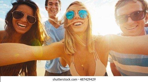 Happy group of friends having fun taking a picture together on the beach - Powered by Shutterstock