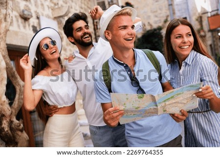 Happy group of friends tourists sightseeing in city on vacation
