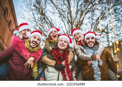 Happy group of friends wearing santa claus hat celebrating Christmas night together - Young people having fun enjoying winter holiday - Teenagers celebrating new year eve - Xmas lifestyle concept - Powered by Shutterstock