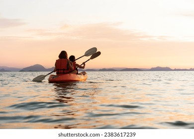 Happy group kayaking at sunset by the sea - Powered by Shutterstock